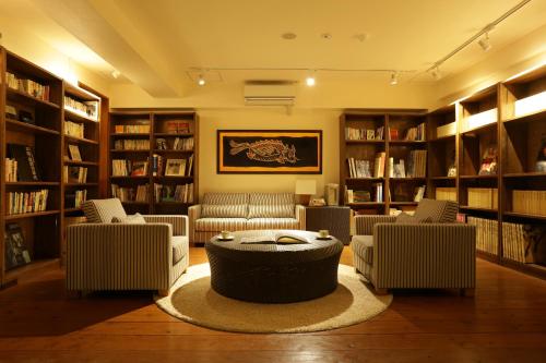 a library with couches and a table and bookshelves at Hyakunagaran in Nanjo