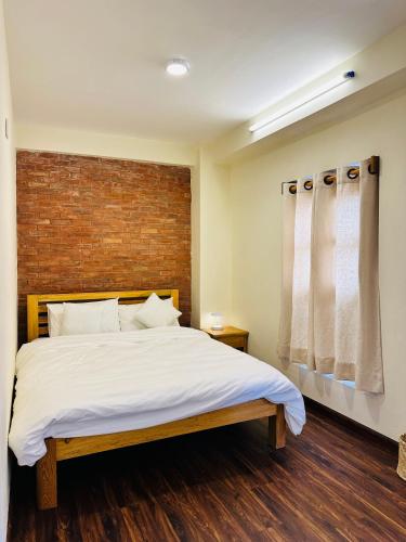 a bedroom with a bed and a brick wall at Yogi's Heritage in Patan-Beautiful Balcony Room in Pātan
