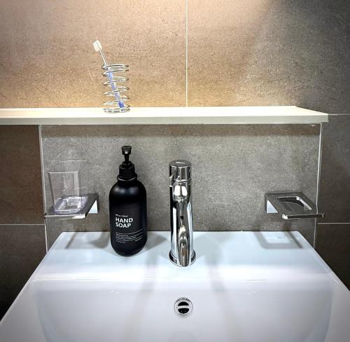 a bathroom sink with a bottle of soap on it at HausKomma 서울 홍대,이태원,명동 짐보관 무료 주차 엘레베이터 새아파트 in Seoul