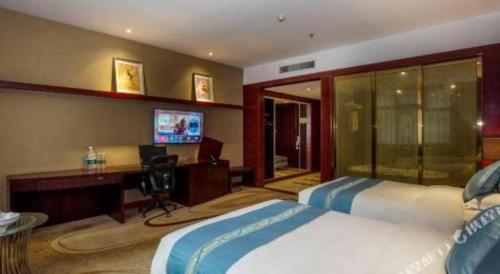 a bedroom with two beds and a desk and a television at Quanzhou Jinjiang Hollyston Hotel in Quanzhou