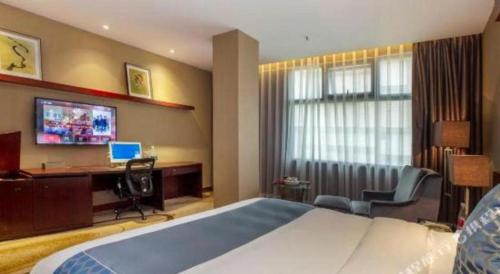 a hotel room with a bed and a desk with a computer at Quanzhou Jinjiang Hollyston Hotel in Quanzhou