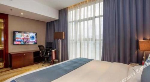 a hotel room with a bed and a flat screen tv at Quanzhou Jinjiang Hollyston Hotel in Quanzhou