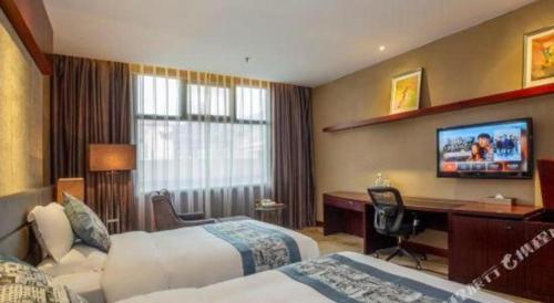 a hotel room with two beds and a desk and a television at Quanzhou Jinjiang Hollyston Hotel in Quanzhou