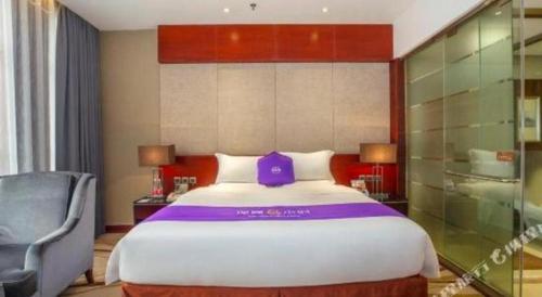 a bedroom with a large bed with a purple pillow on it at Quanzhou Jinjiang Hollyston Hotel in Quanzhou