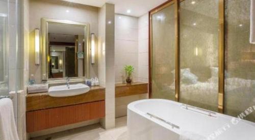 a bathroom with a tub and a sink and a shower at Quanzhou Jinjiang Hollyston Hotel in Quanzhou