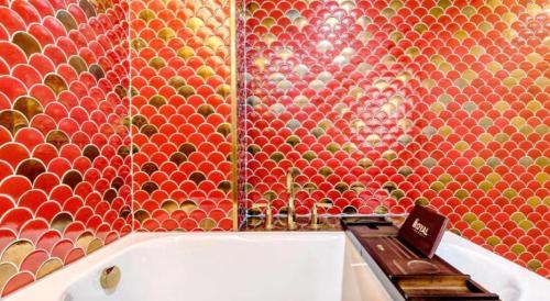 a bathroom with a tiled wall with a bathtub with a clock on it at James Joyce Coffetel·Anyang Text Museum in Anyang