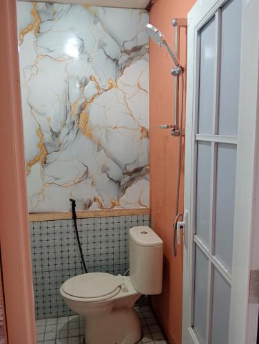 a bathroom with a toilet and a marble wall at Arthuro homestay in Si Antar