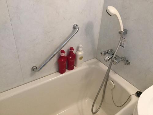 a bathroom with two red bottles on the bath tub at Hotel Gran View Garden Okinawa in Tomigusuku