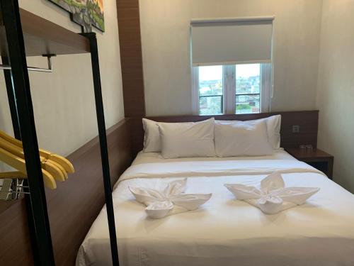 a bedroom with a bed with two white flowers on it at Hotel Travel Biz in Medan