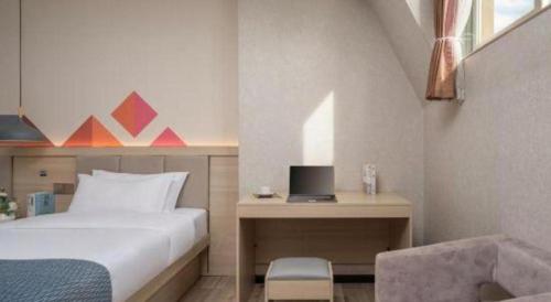 a bedroom with a bed and a desk with a laptop at Borrman Hotel Yuxi Yuxing Road in Yuxi