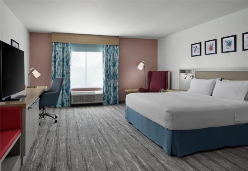 a hotel room with a bed and a flat screen tv at Hilton Garden Inn Tampa East Brandon in Tampa