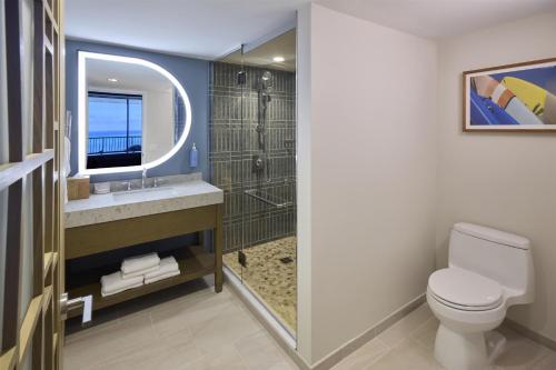 a bathroom with a toilet and a sink and a mirror at Hilton Hawaiian Village Waikiki Beach Resort in Honolulu