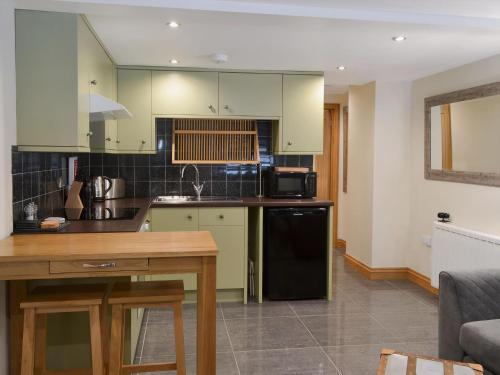 een keuken met groene kasten en een zwarte koelkast bij Rockfish Cottage in Brixham