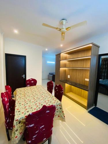 a dining room with a table and some red chairs at The SUNset, Zirakpur 3bhk flat for families only in Zirakpur