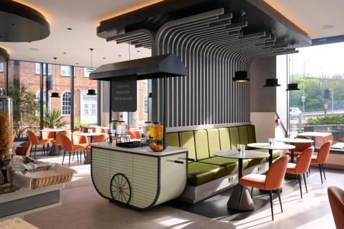 a restaurant with a stove and some tables and chairs at Spark by Hilton Luton in Luton
