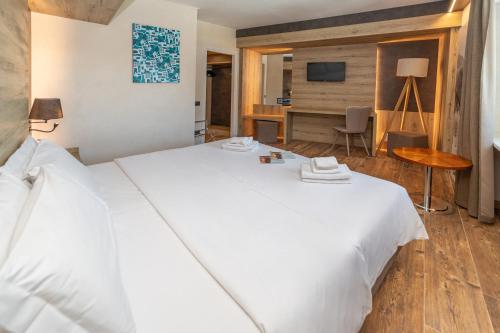 a bedroom with a large white bed and a desk at Hotel la Torre in Sauze dʼOulx