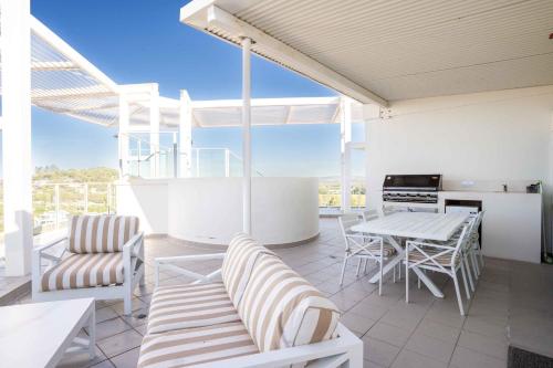 a patio with a table and chairs and a kitchen at Coastal Penthouse 3BR Luxe Living Over Kirra Beach in Gold Coast