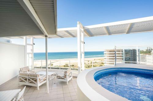 a balcony with a swimming pool and the ocean at Coastal Penthouse 3BR Luxe Living Over Kirra Beach in Gold Coast