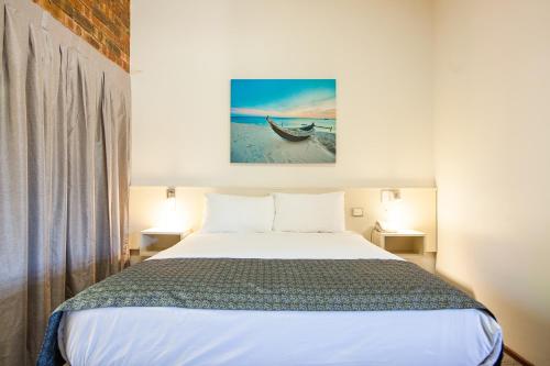 1 dormitorio con 1 cama y una foto de un barco en Leisure Inn Hotel Rockingham, en Rockingham