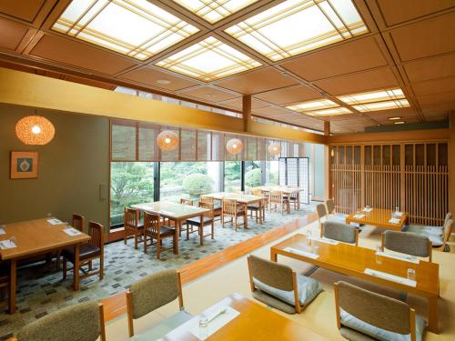 a dining room with tables and chairs and windows at Shizuoka Country Hamaoka Course & Hotel in Omaezaki