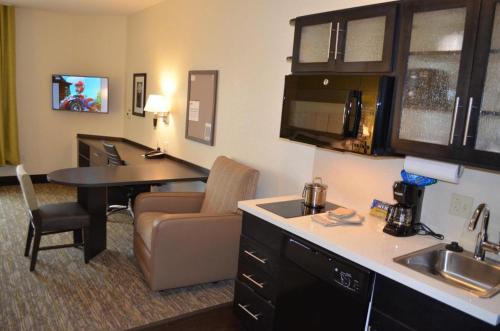 eine Küche mit Spüle und Tisch in einem Zimmer in der Unterkunft Candlewood Suites Saint Joseph By IHG in Saint Joseph