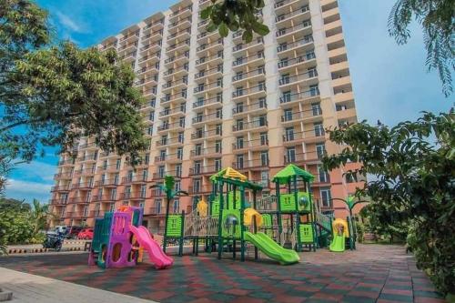 un parque infantil frente a un gran edificio en Mactan cozy nest 1619, en Lo-oc