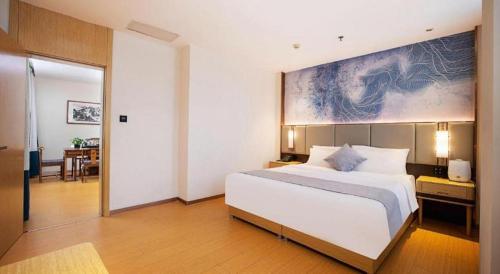 a bedroom with a large bed with a painting on the wall at GreenTree Inn Taiyuan PinGYAng Road Business Hotel in Taiyuan