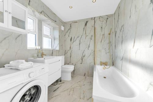 ライにあるPass the Keys Mermaids Rest - Stylish Flatの洗面台と洗濯機を備えた白いバスルーム