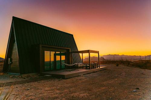 a small green building with a porch and a chair at Stardust Big Bend Luxury A-Frame#2 with a fab view in Terlingua