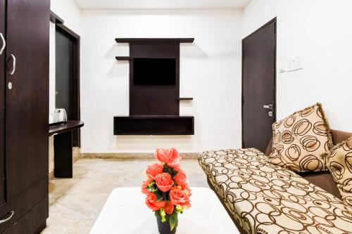 a living room with a couch and a vase with flowers at Hotel O Raipur City Center Formerly Hotel Edge in Raipur