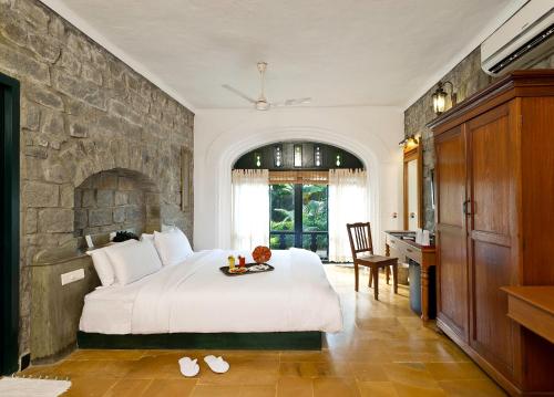 - une chambre avec un grand lit et un mur en pierre dans l'établissement Sparsa Resort Thiruvanamalai, à Tiruvannāmalai
