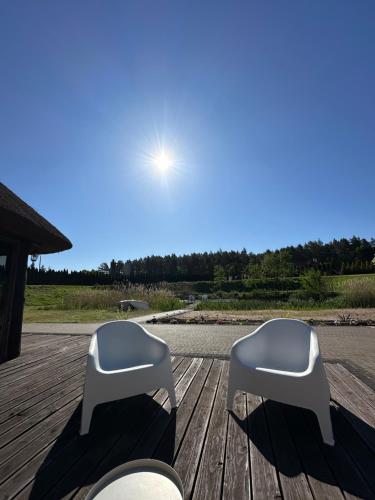 two white stools sitting on a wooden deck at Cabin by the pond in Wądołki Bućki