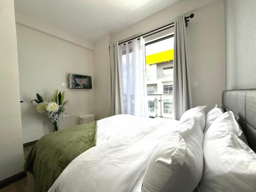 Un dormitorio con una cama blanca y una ventana. en Kilimani Executive Suites With Gym, Heated Pool, Sauna, Steam room, en Nairobi