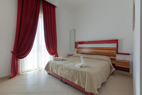 a bedroom with a large bed with red curtains at diVino Hotel in Rilievo