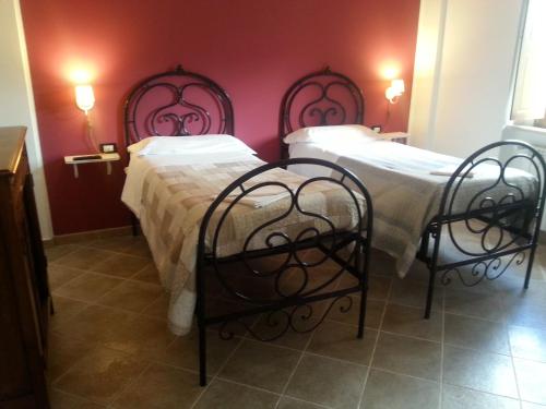 2 łóżka w pokoju z czerwonymi ścianami w obiekcie Il GIARDINACCIO Agriturismo w mieście LʼAquila