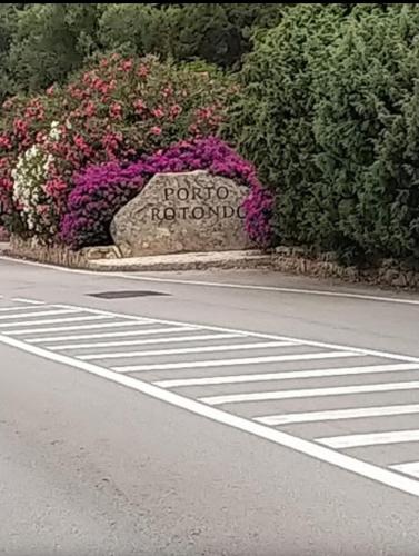 a sign on the side of a road with flowers at Apartments Nicole in Porto Rotondo