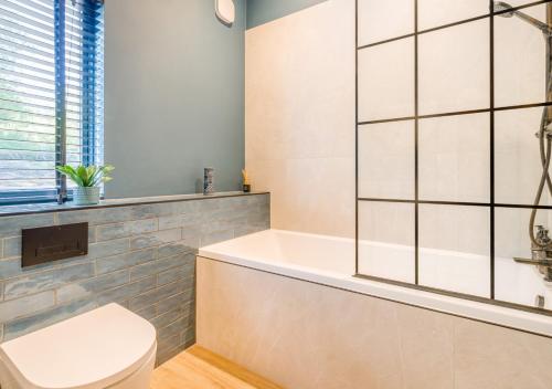 een badkamer met een wit bad en een toilet bij Deer Cottage in Eldroth