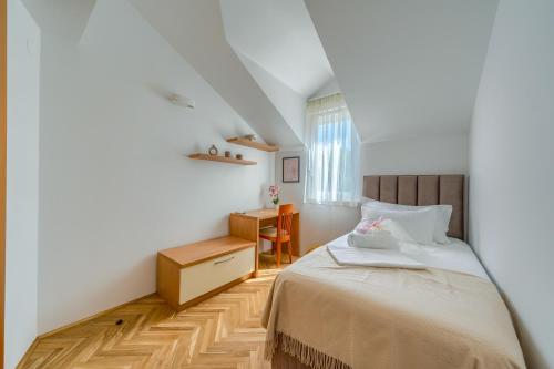 een slaapkamer met een bed, een bureau en een raam bij Apartments Eternity in Split