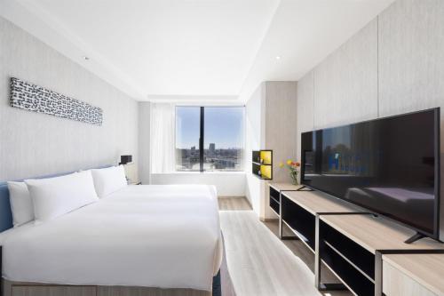 a bedroom with a large white bed and a flat screen tv at Hyatt House Tokyo Shibuya in Tokyo
