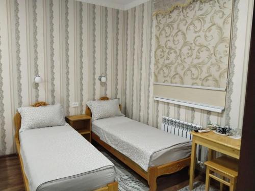 two twin beds in a room with wallpaper at Гостевой дом Hotel Allanazar Ota in Khiva