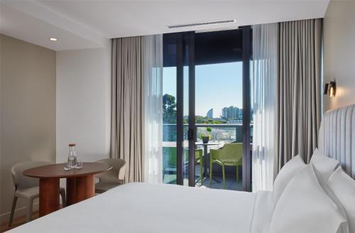 a hotel room with a bed and a view of a balcony at Hyatt House South Melbourne in Melbourne