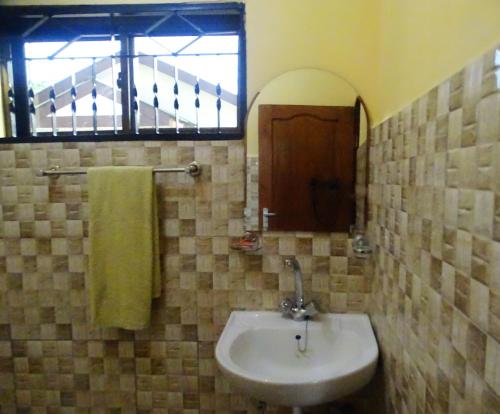 a bathroom with a sink and a mirror and a window at Mgulani Lodge Hotel in Dar es Salaam