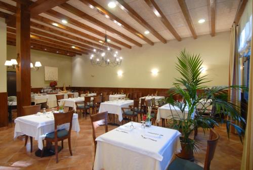 a restaurant with white tables and chairs and a chandelier at Hotel Florido in Sort
