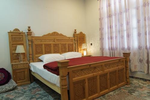 a bedroom with a wooden bed with a red blanket at Mountain Villa - Hunza Valley in Hunza