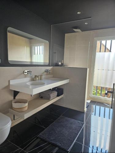 une salle de bain avec un lavabo et un miroir dans l'établissement Appart design Jacuzzi Sauna, Salle de sports, à Emmerin