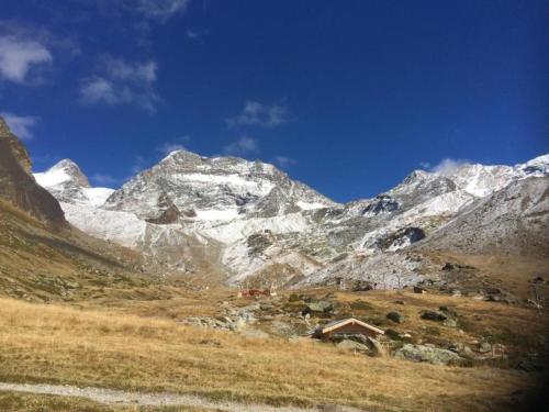 a snowy mountain range with a house in the foreground at Chalet Stadel Alpine Comfort in Saas-Grund
