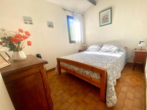 - une chambre avec un lit et un vase de fleurs dans l'établissement Maisonnette 6 personnes proche plage – Animaux acceptés, au Grau-du-Roi