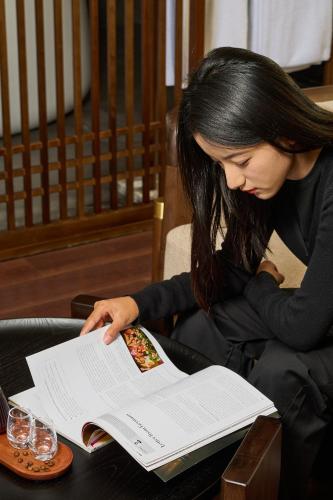 a woman sitting at a table reading a book at ARULA J Hotel in Lijiang