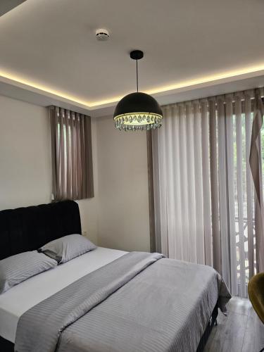 a bedroom with a large bed and a chandelier at La Vida Apartments in Babalonija