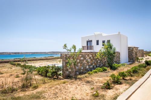 a house on the beach with the ocean in the background at Cato Agro 1, Seafront Villa with Private Pool in Karpathos Town
